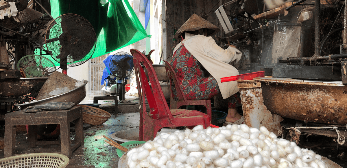 Traditional silk workshop with baskets of white cocoons.