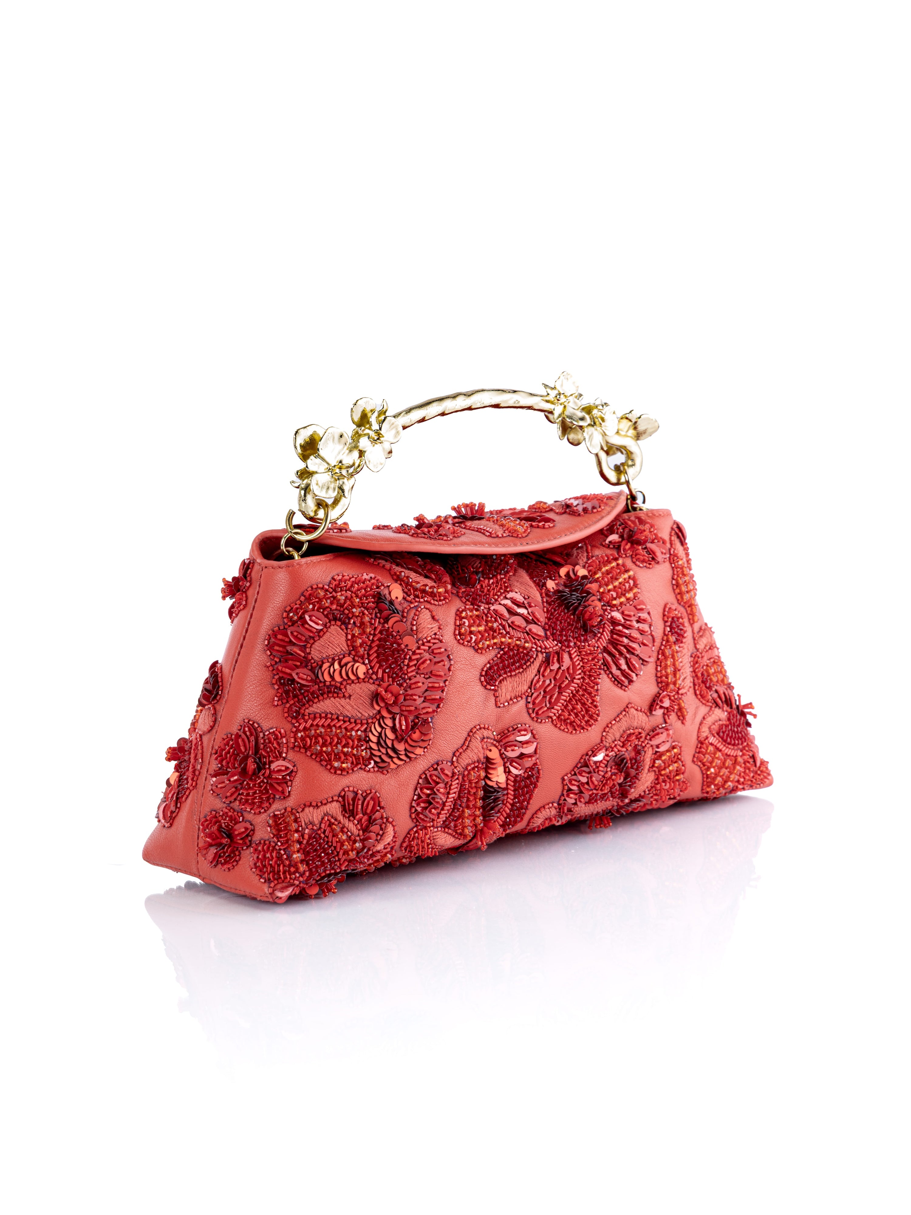 A coral red textured clutch Red Siren Rose handbag with intricate red floral embroidery, a gold-tone chain handle, and a small top flap, shown on a white background with a soft reflection.