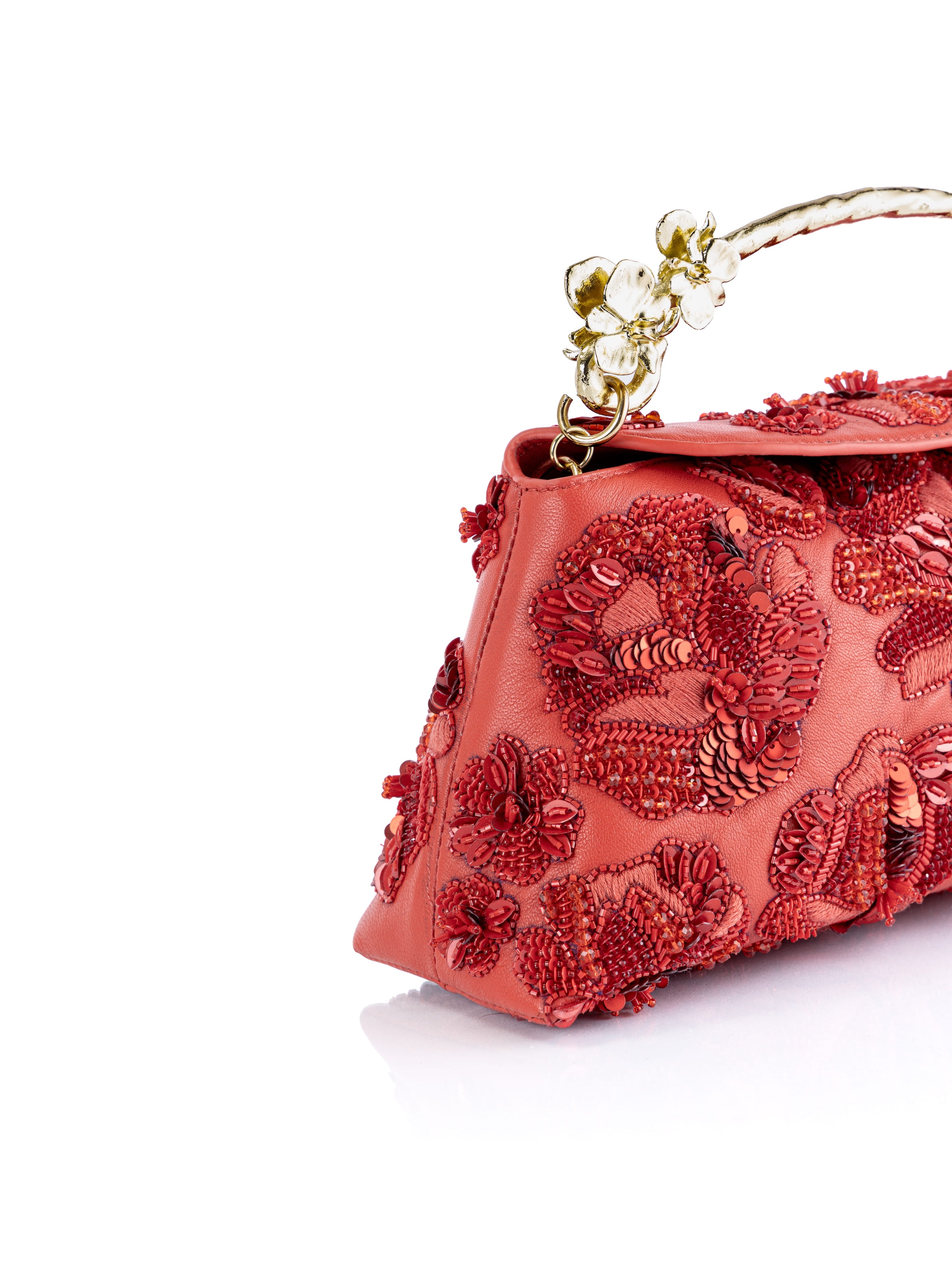 A close-up of a coral red evening Red Siren Rose clutch bag featuring intricate 3D floral embroidery, beadwork, and a gold-tone handle adorned with clear crystals, set against a plain white background.