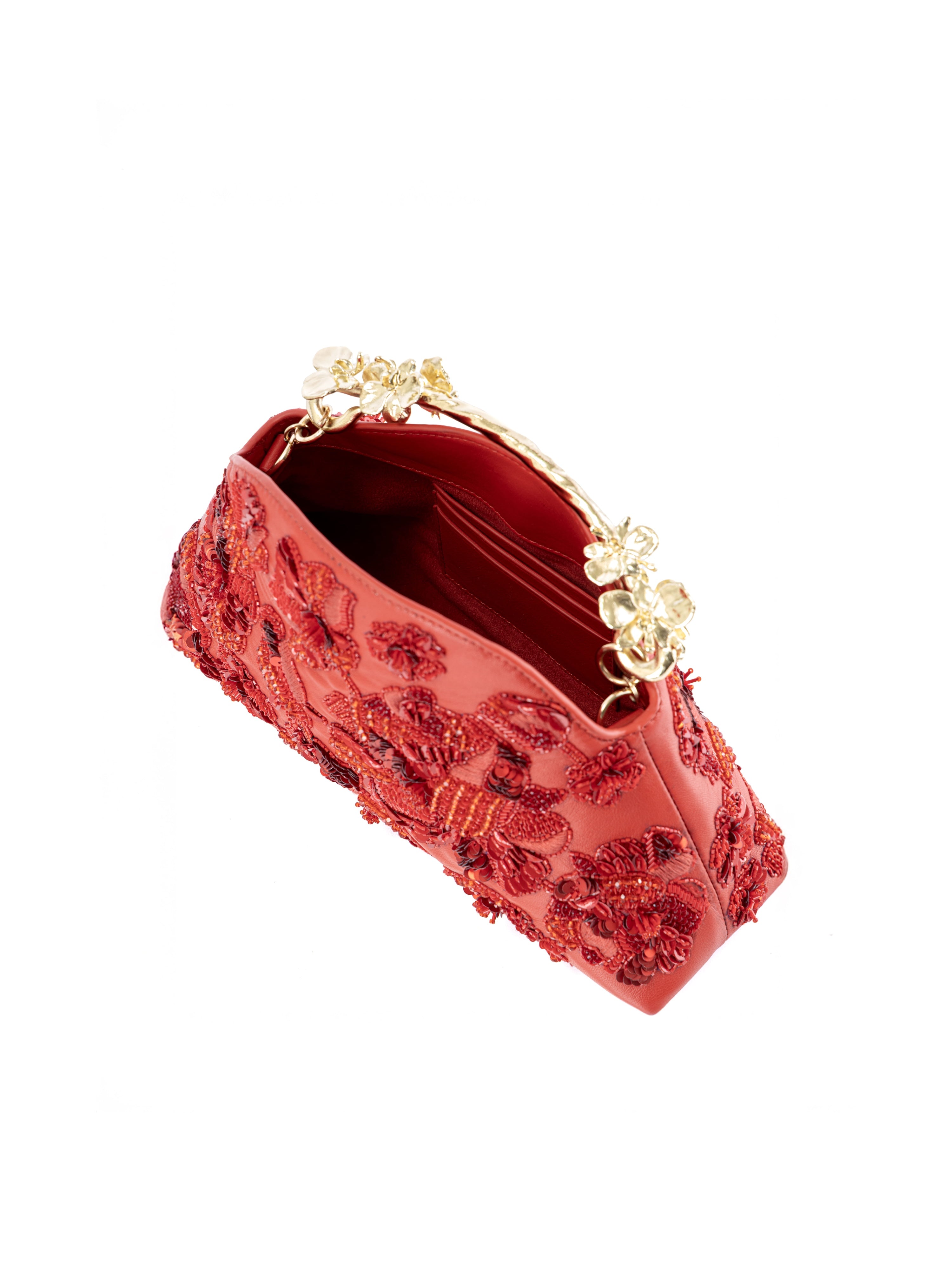 A red textured clutch Red Siren Rose bag with intricate floral embroidery and gold-tone metal floral accents on the handle, shown against a plain white background.