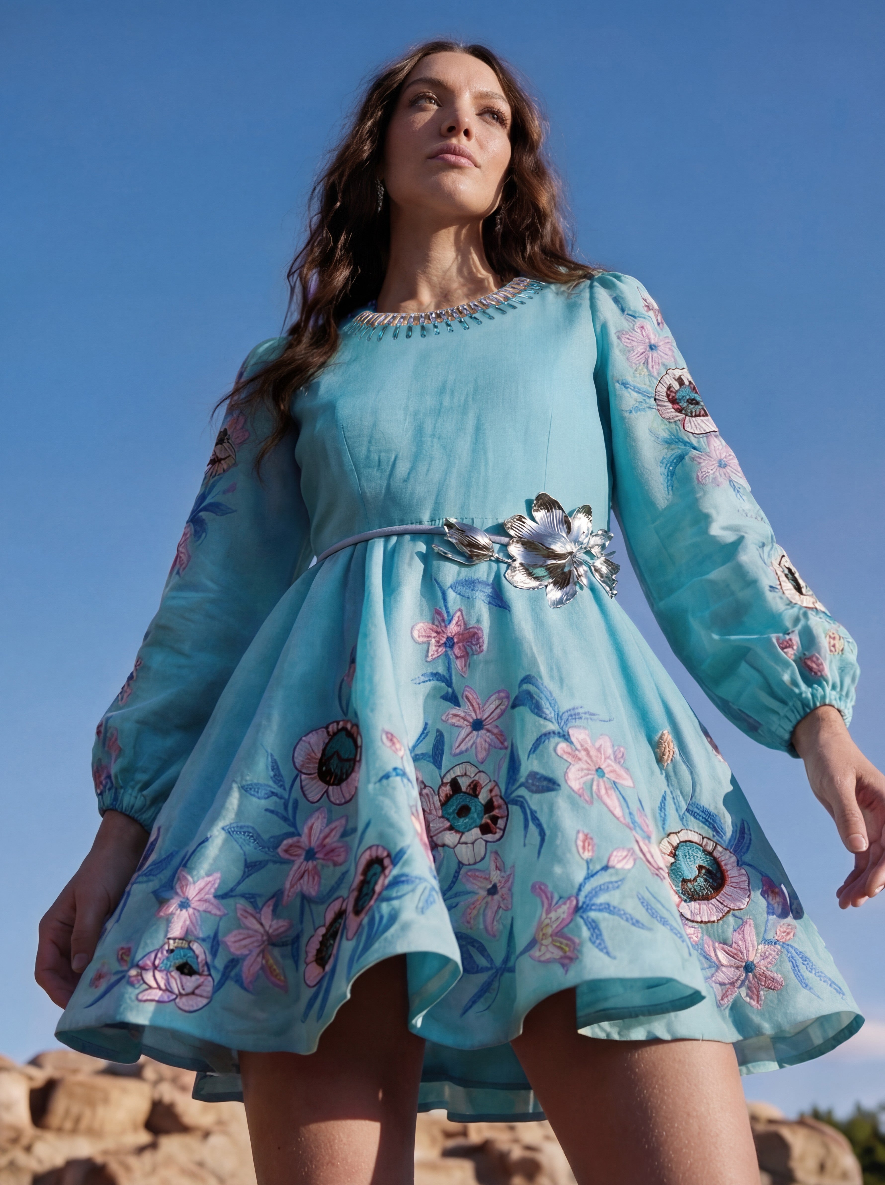 Woman wearing a blue floral dress against a clear blue sky.