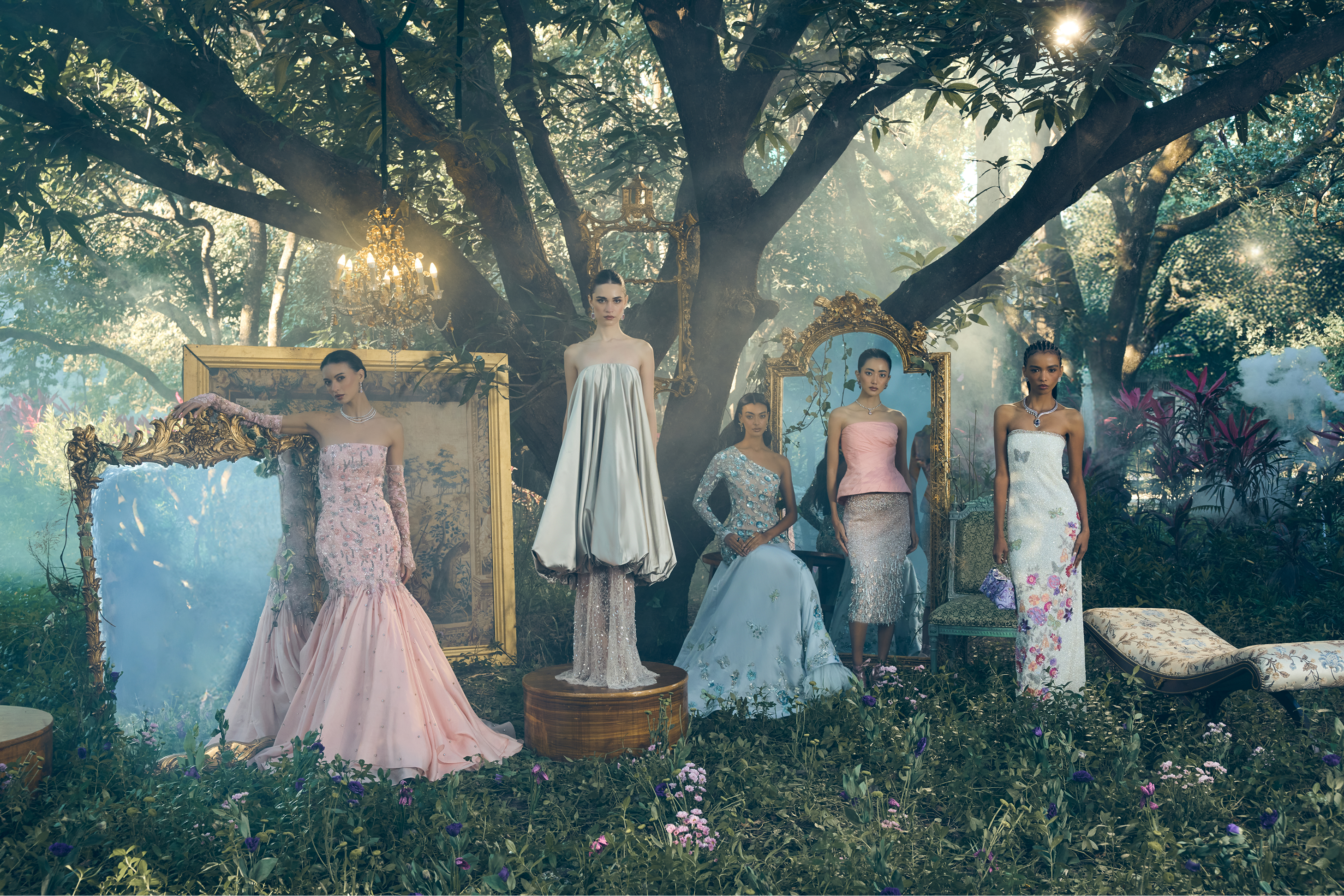 Models in elegant dresses in a forest setting with large mirrors and decorative elements.