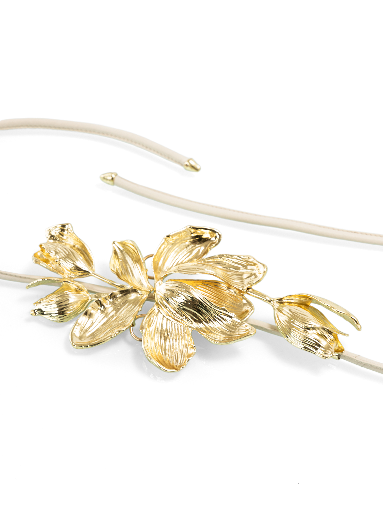 Close-up of the refined metal flower buckle showcasing fluid form and sculptural detailing
