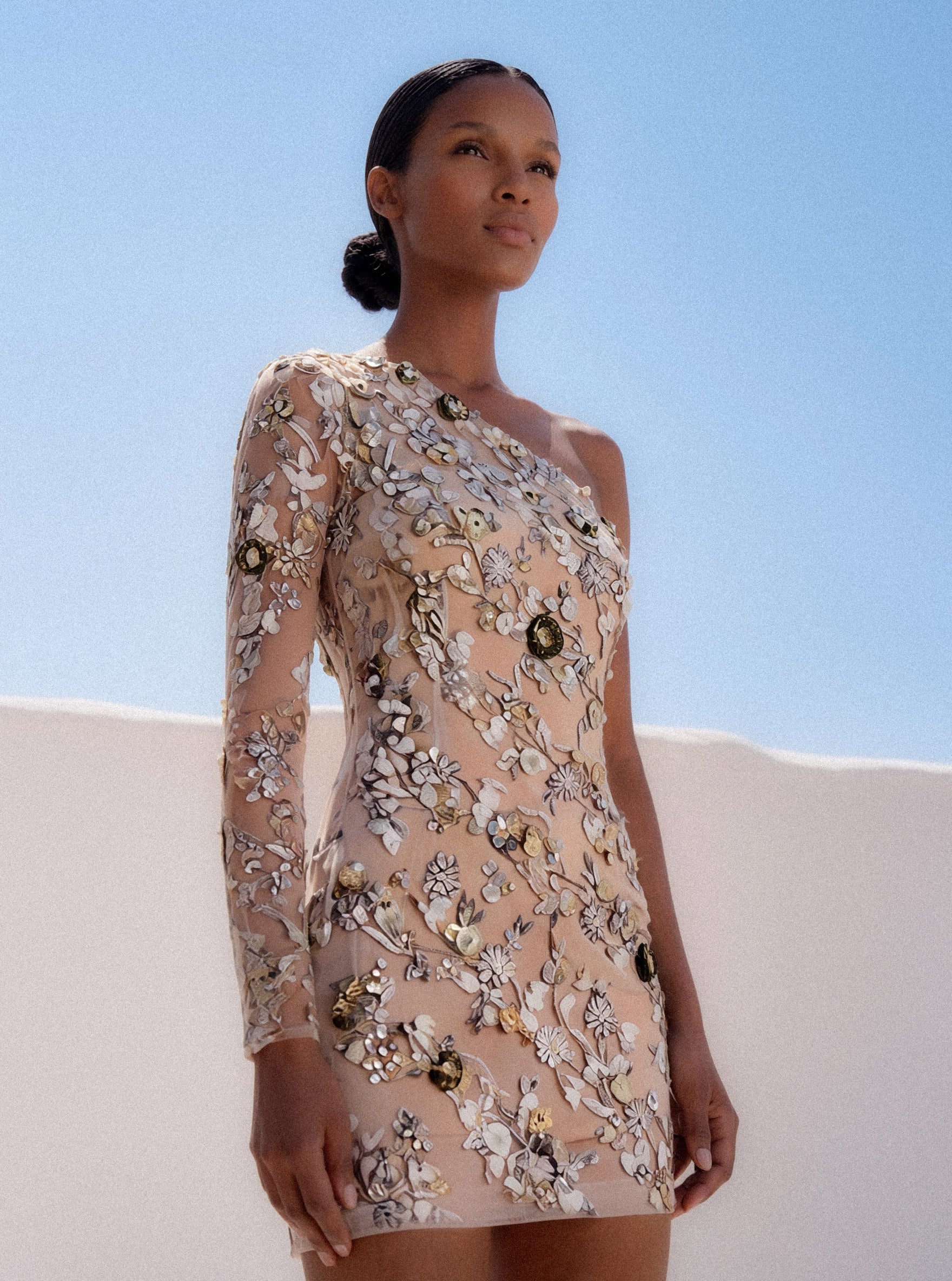 Woman wearing a floral dress against a clear blue sky.