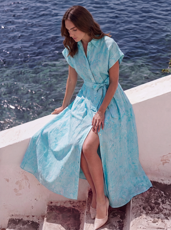 Woman in a blue dress sitting by a body of water