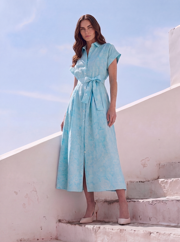 Woman in a light blue dress standing on white steps with a clear sky background