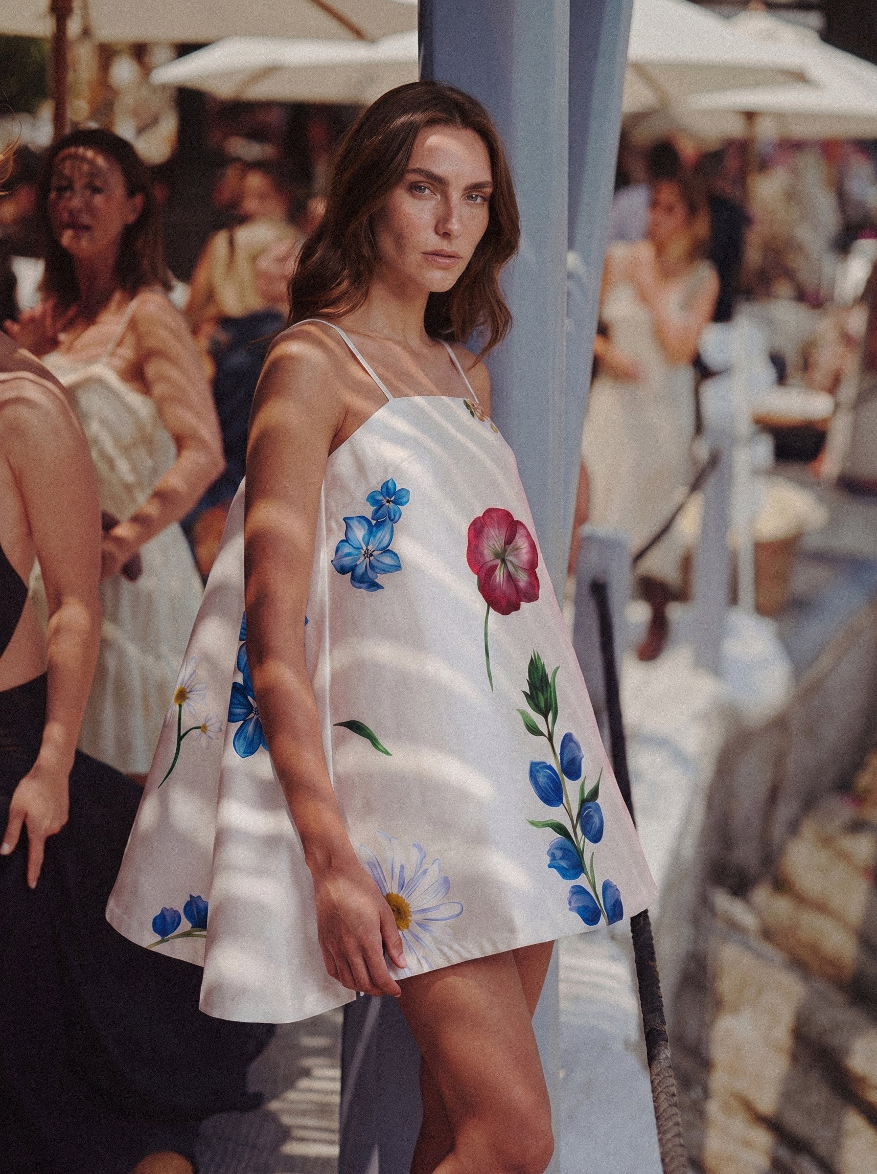 Woman wearing a white dress with floral embroidery in a bustling outdoor setting