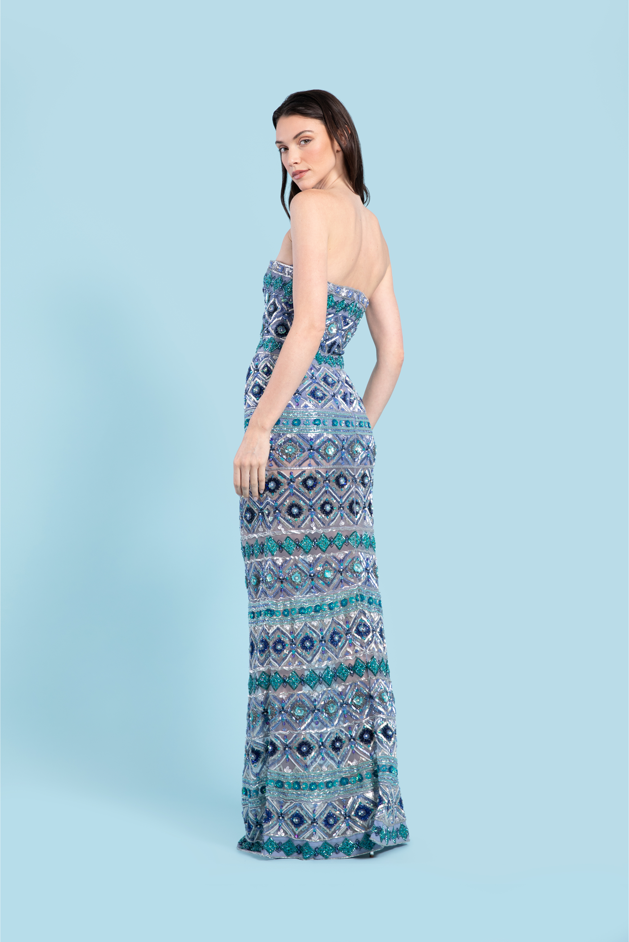 Woman wearing a strapless, patterned dress against a light blue background