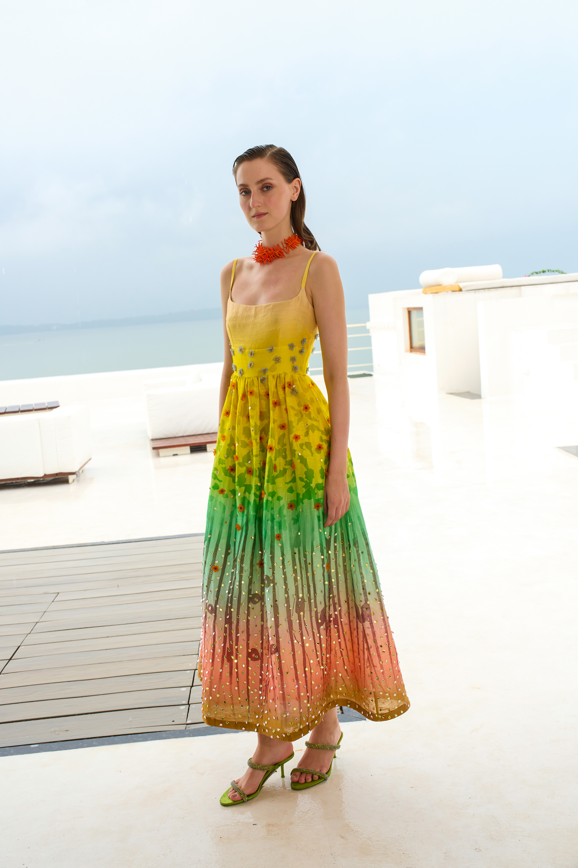 Woman wearing a colorful gradient dress on a rooftop with ocean view