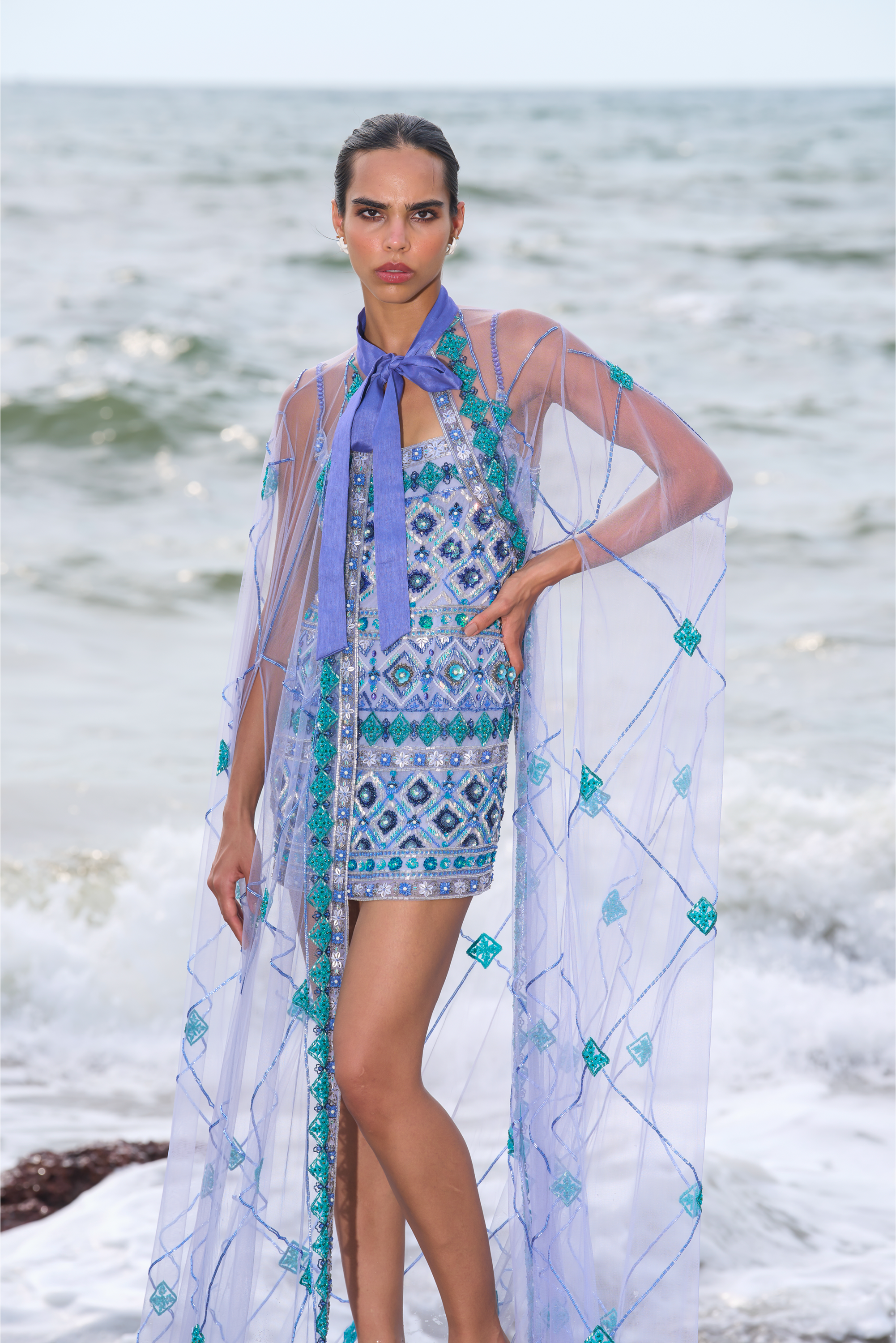 Woman in a stylish outfit with a scarf by the ocean