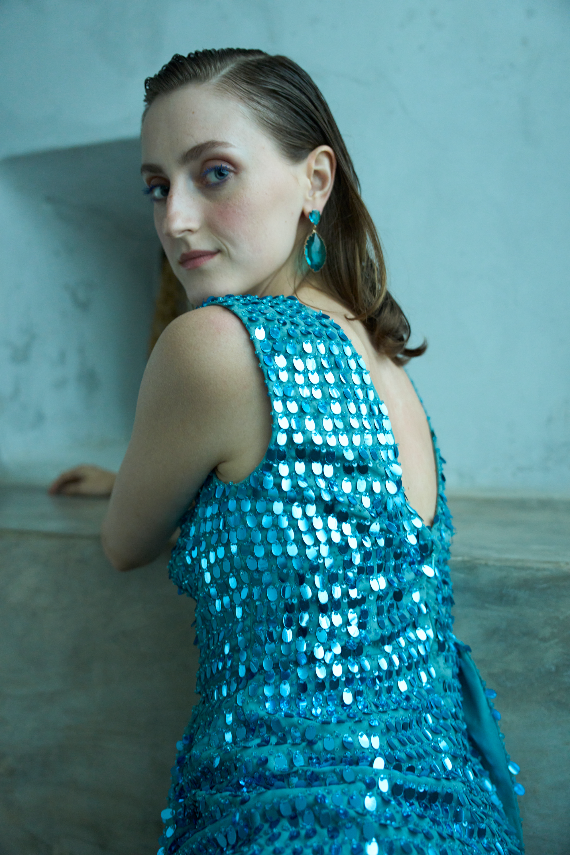 Woman wearing a blue sequin dress with a plain background