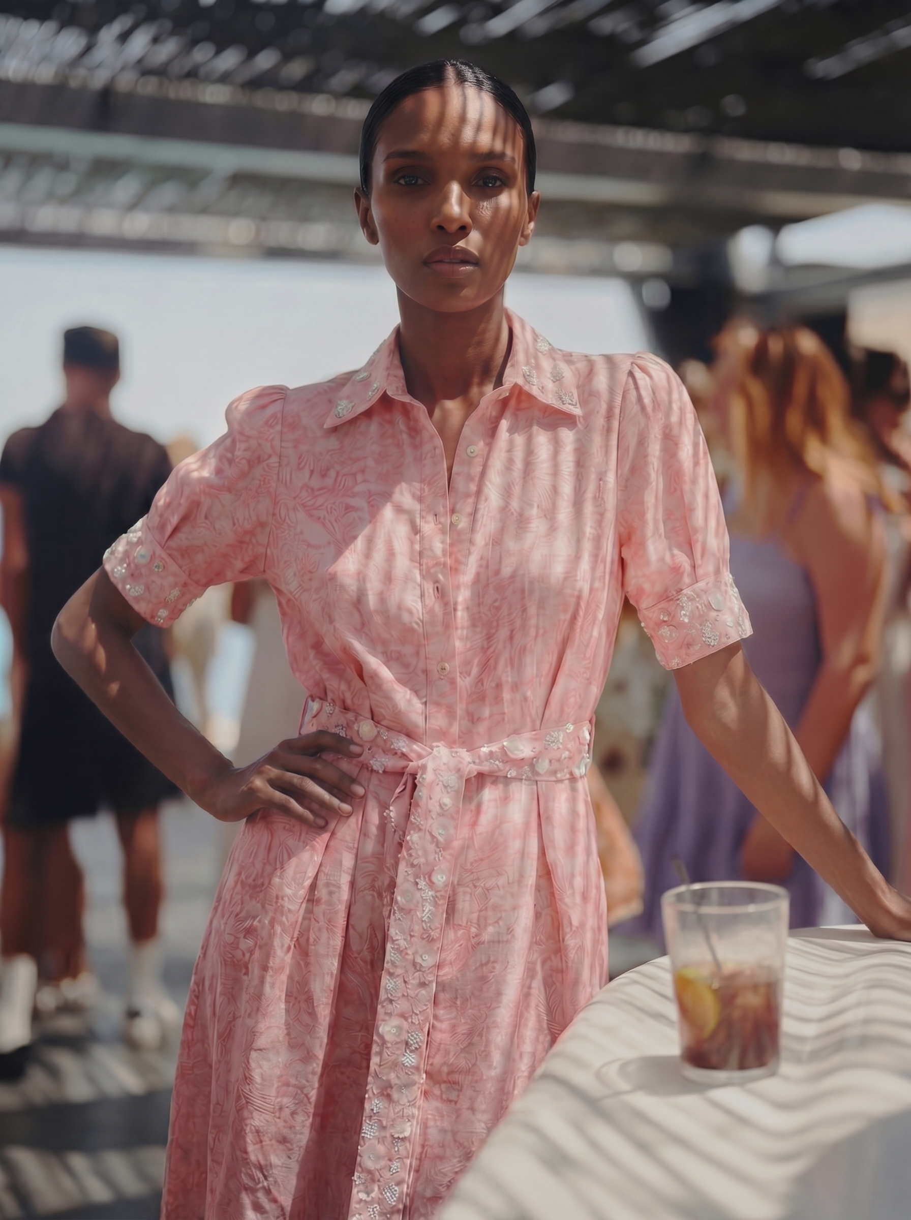 Woman in a pink dress standing outdoors with people in the background