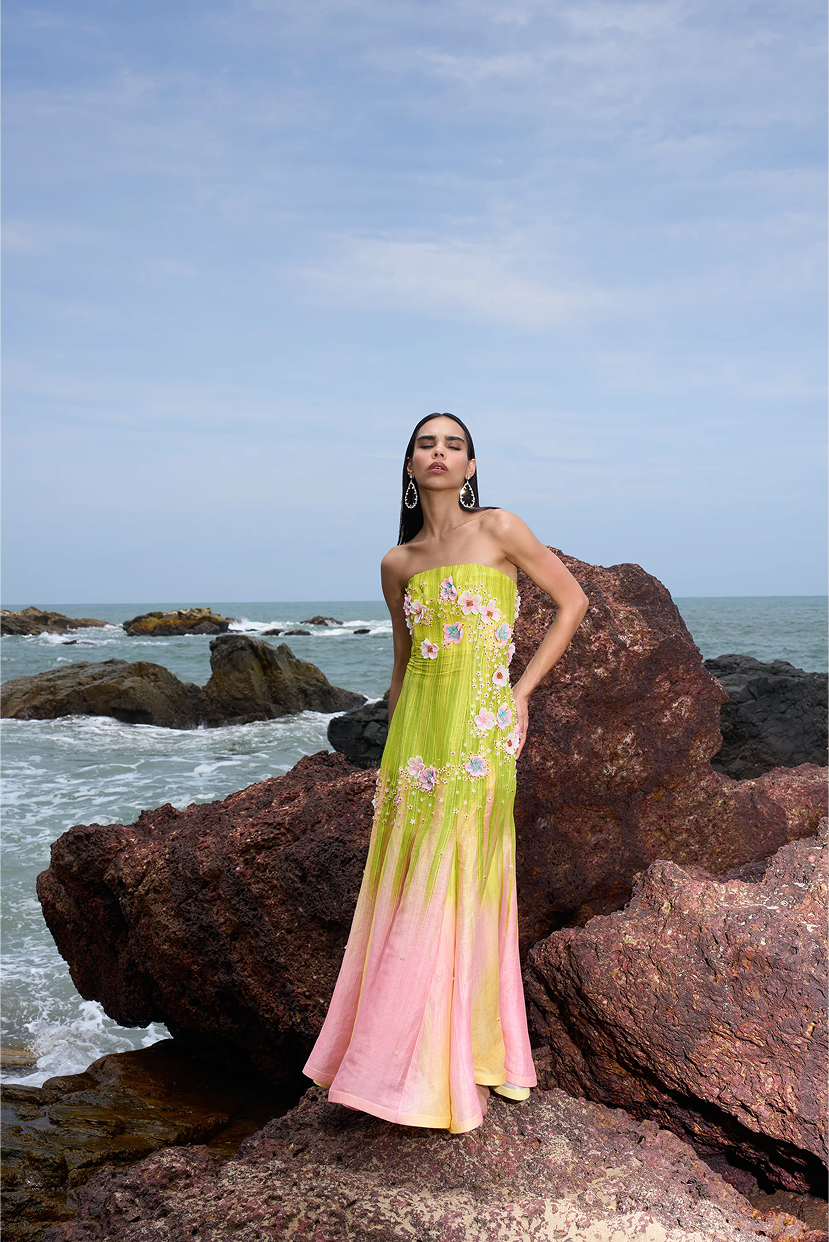 Woman in a colorful dress standing on rocks by the ocean