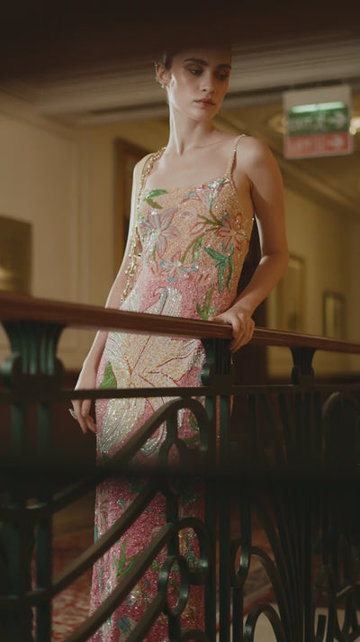 Model posing in a detailed embroidered dress featuring delicate threadwork and flowing fabric.